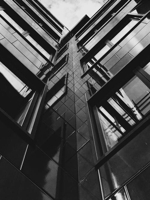 Фотография высотного здания в оттенках серого под низким углом