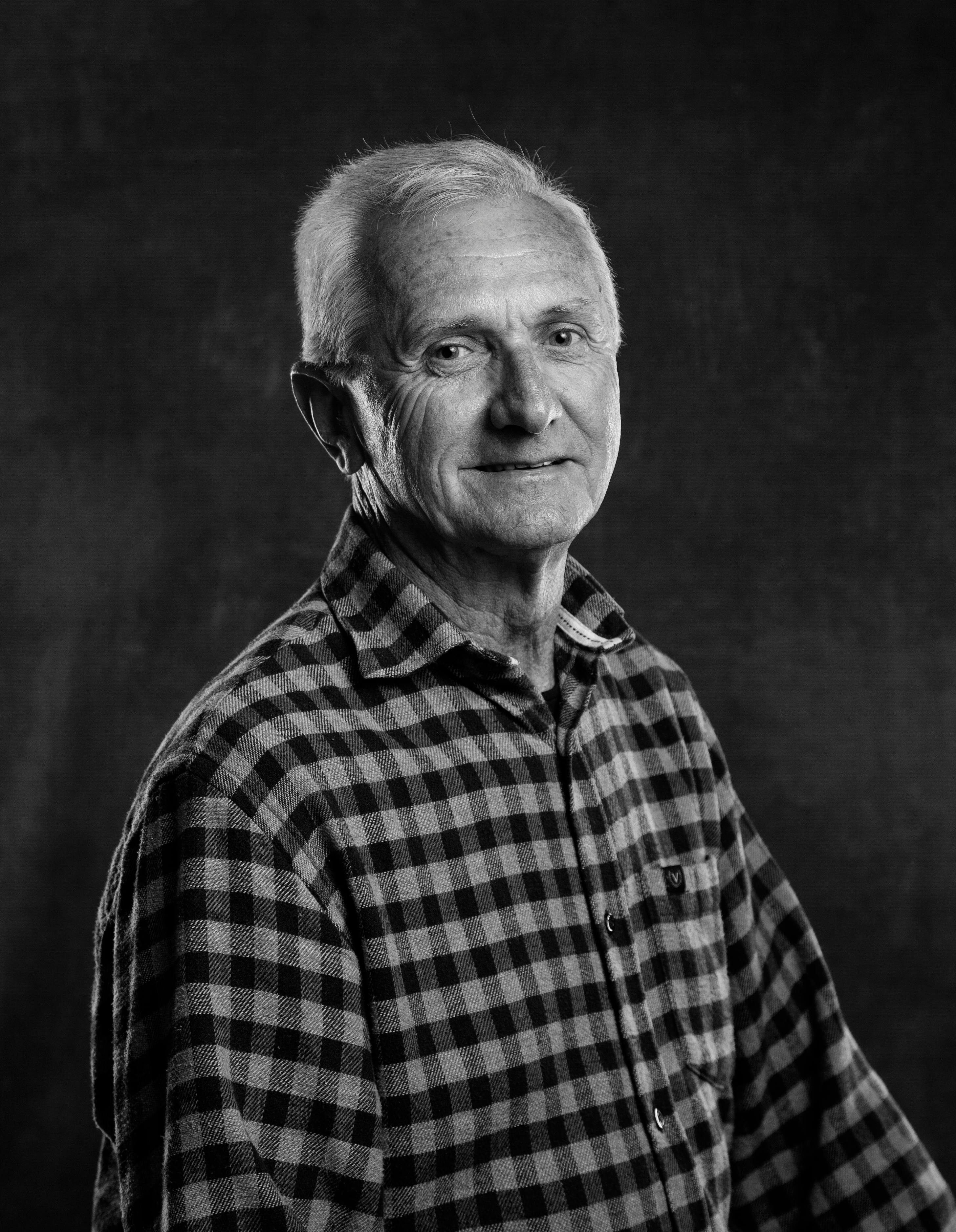 A serene studio portrait of an elderly man in a checkered shirt, exuding wisdom and warmth.