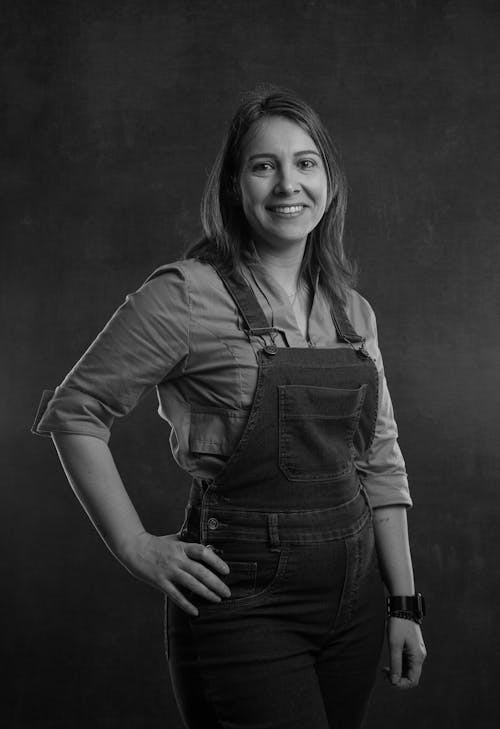 A woman in overalls posing for a black and white photo