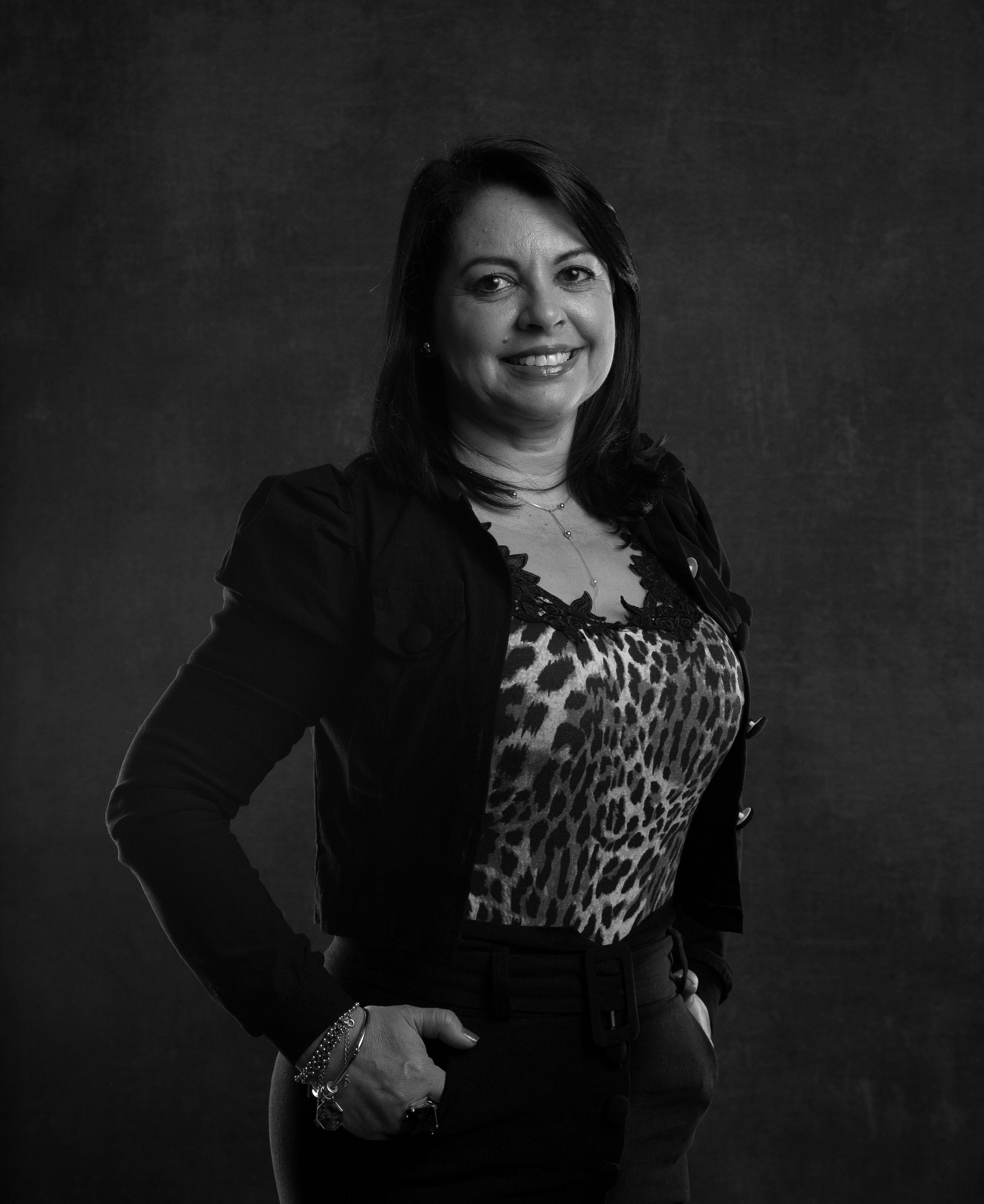 Black and white portrait of an elegant woman posing in a studio with animal print attire.