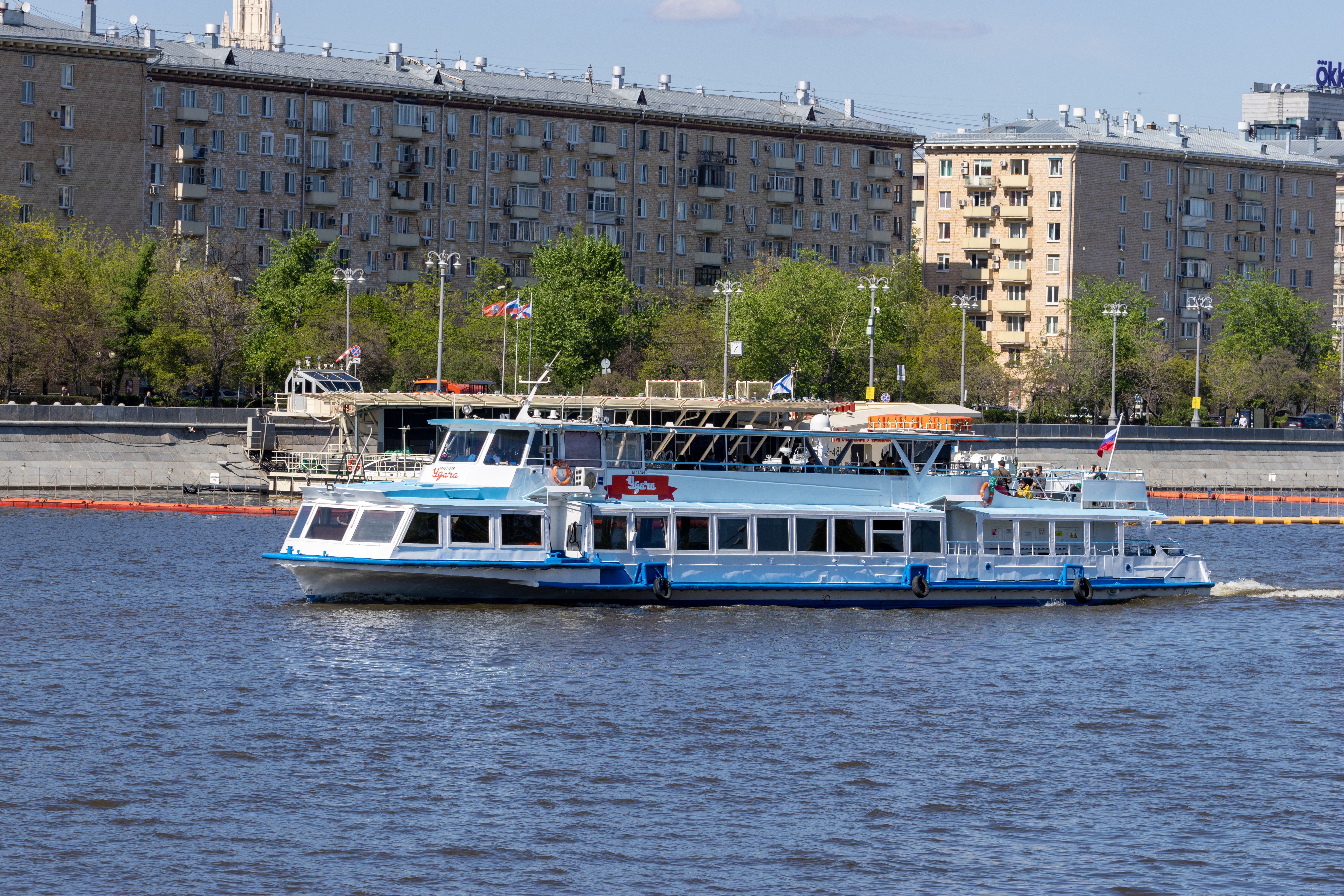 бесплатная Речной пароход движется вдоль города, на заднем плане видны многоквартирные дома. Стоковое фото