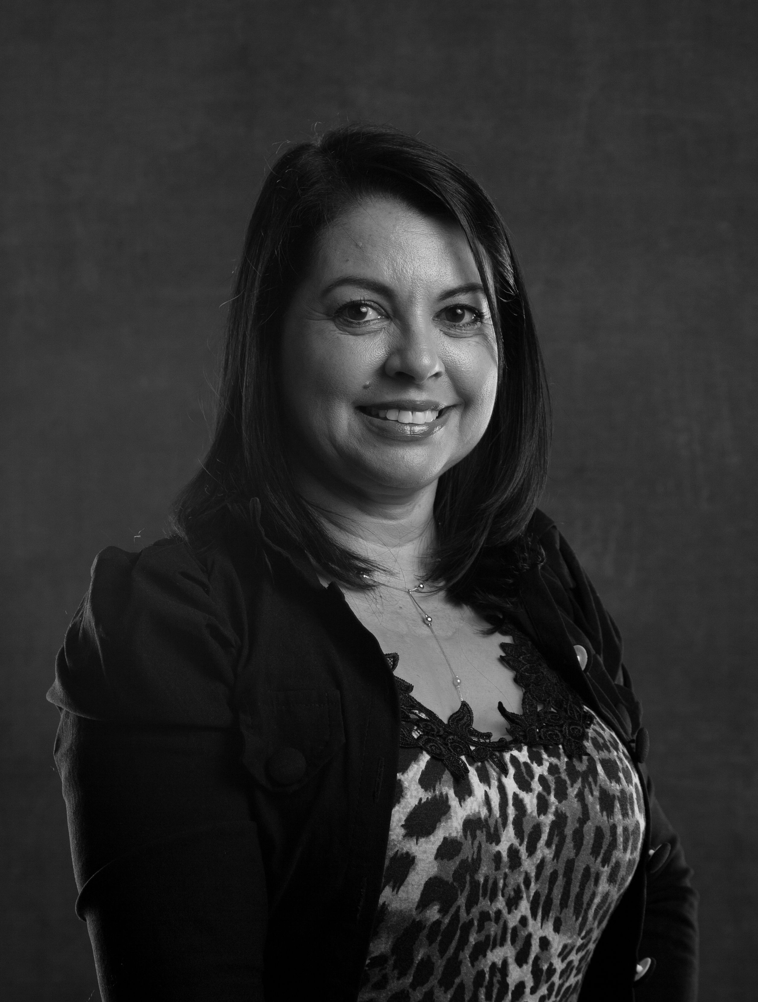 Elegant studio portrait of a smiling woman in monochromatic attire.