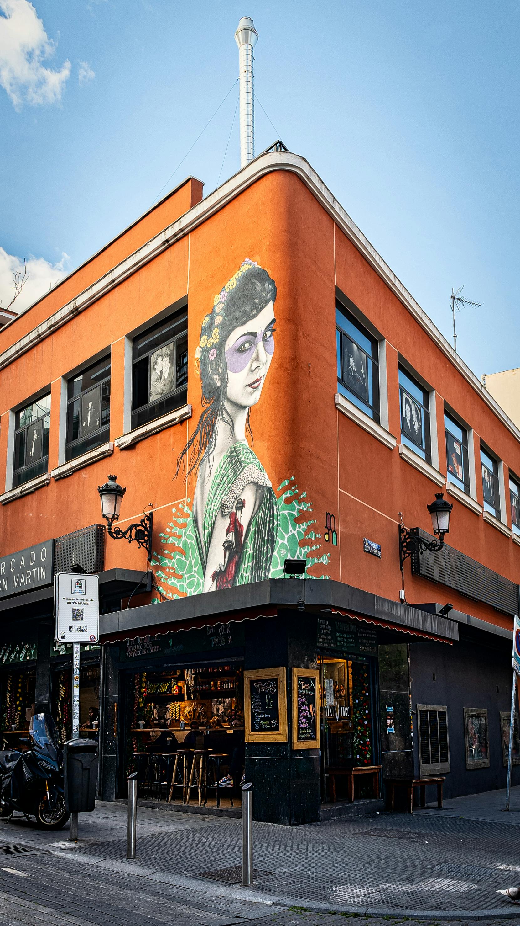 Colorful mural on an urban building corner, blending art with city life.