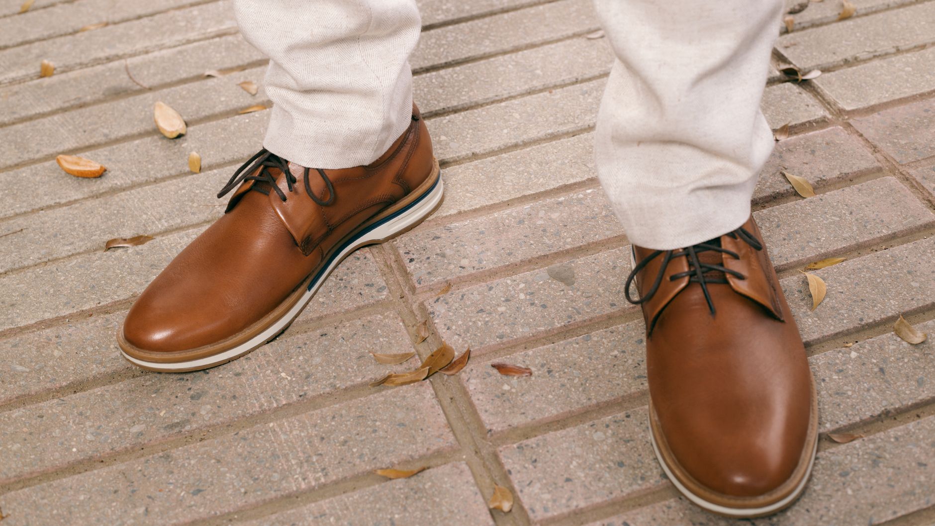 Close-up of a man's brown leather shoes on a city pavement.