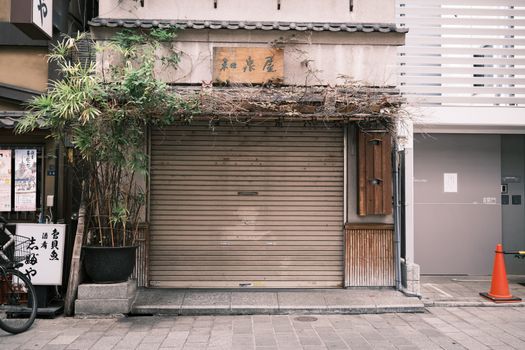 Closed storefront in Tokyo, Japan, featuring traditional facade and potted plants.