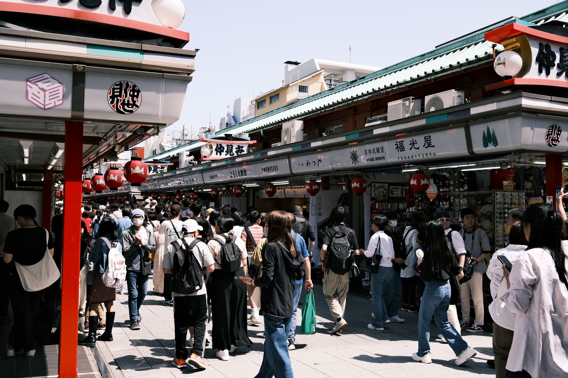 Bustling Nakamise Street in Tokyo with crowds and traditional shops.