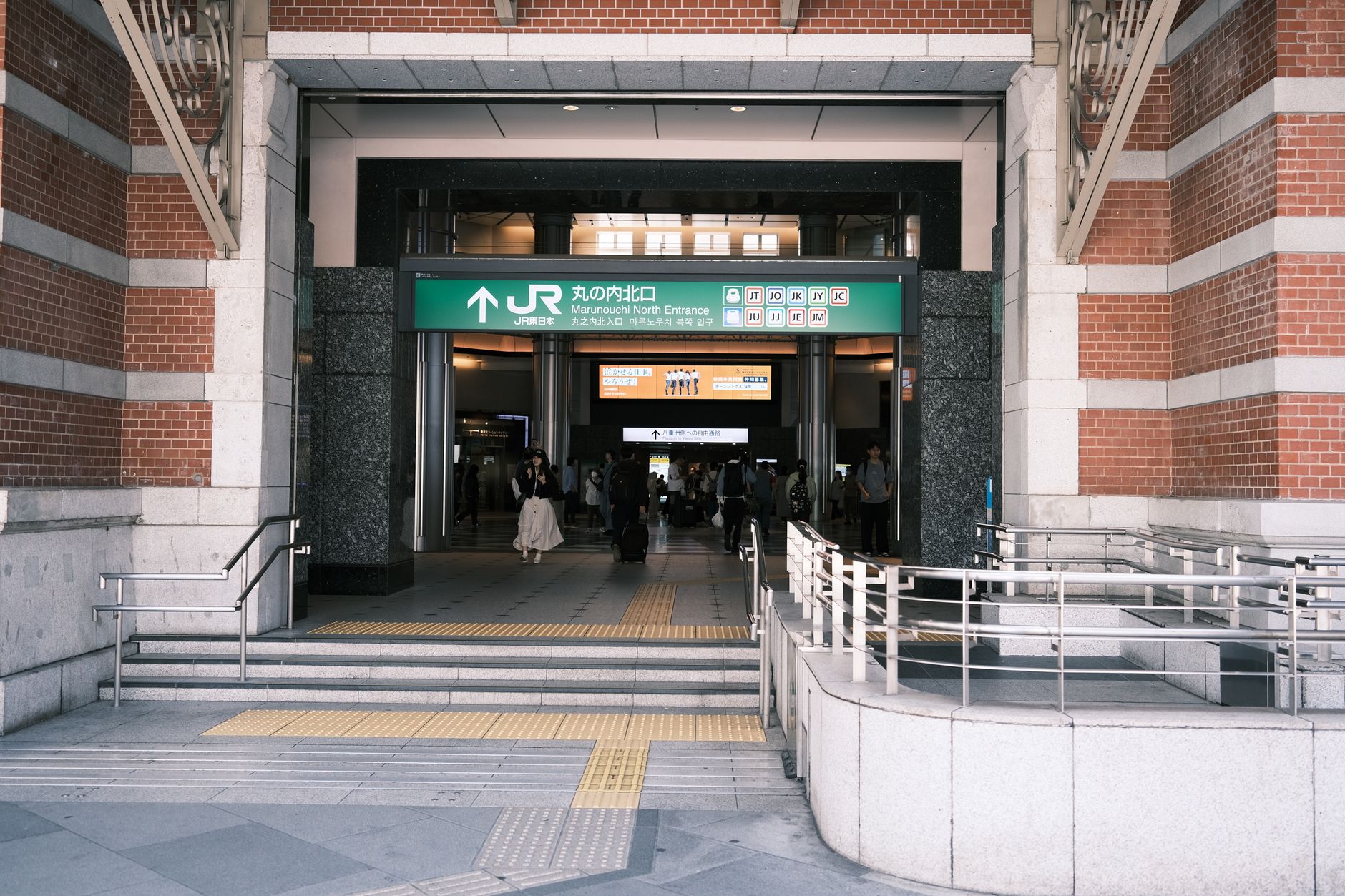Entrance to Tokyo Station's Marunouchi North Entrance with people and signage visible.