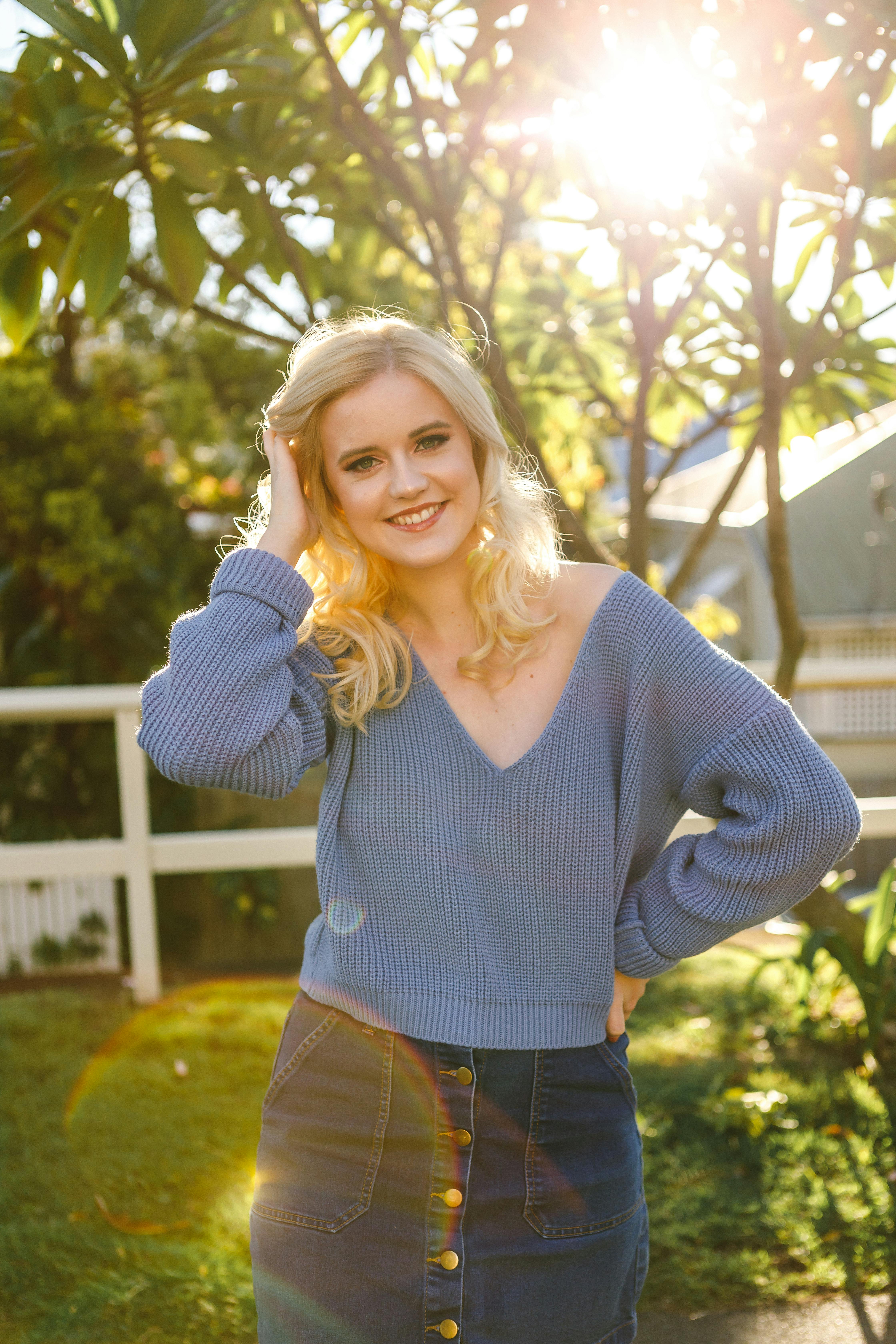 一位金发女人在阳光明媚的户外场景中热情微笑，展现时尚与风格