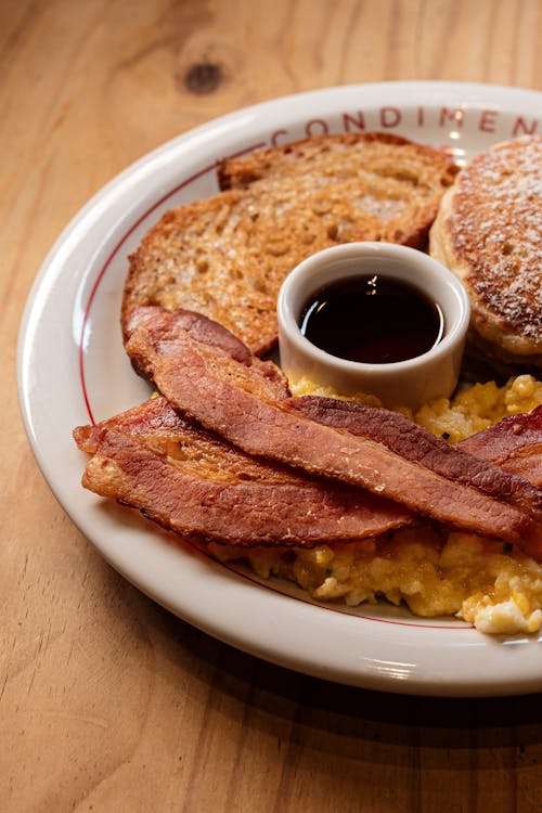 A plate of breakfast food with bacon, eggs and toast