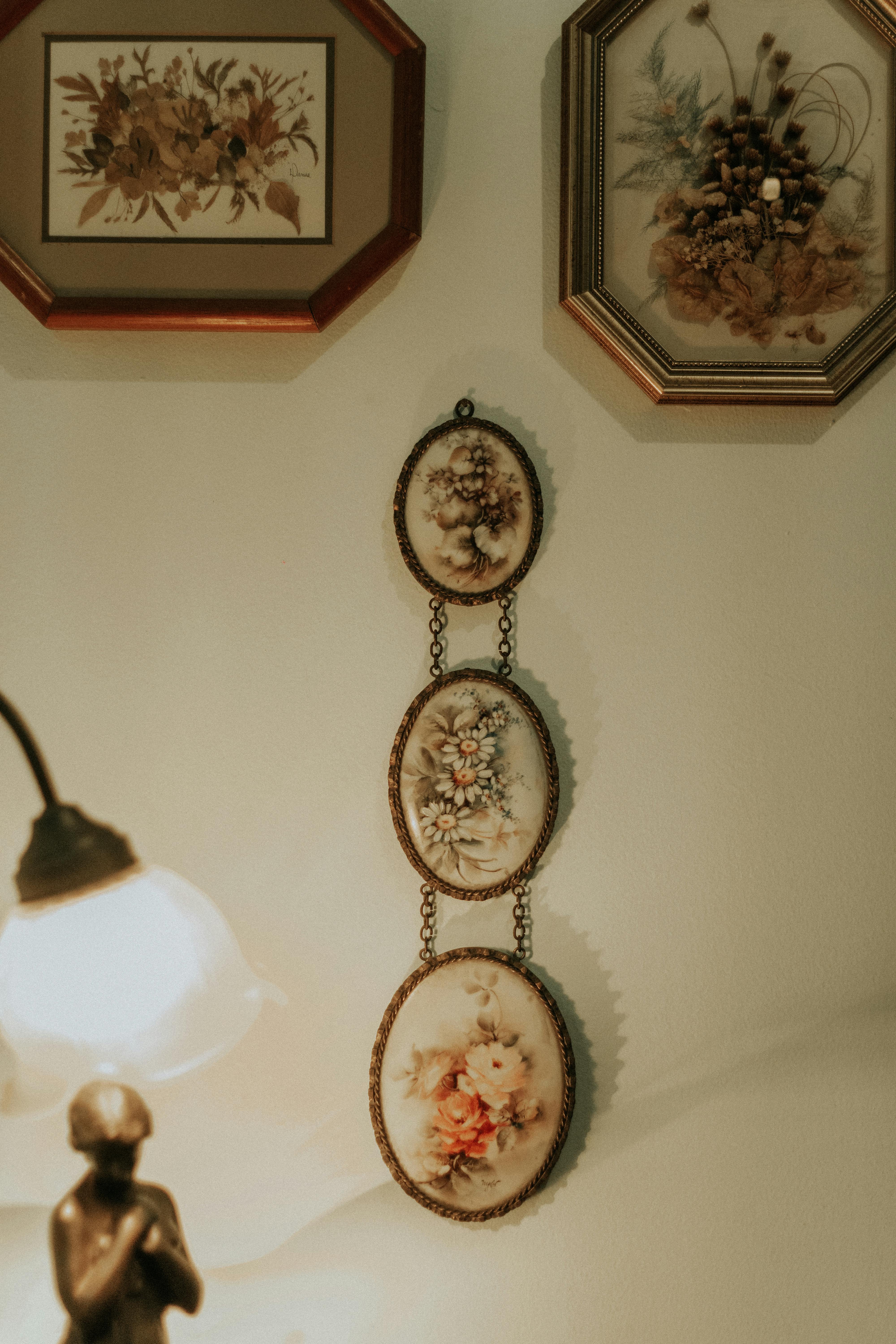 Elegant vintage wall decor featuring floral artwork and a classic lamp casting a warm glow.