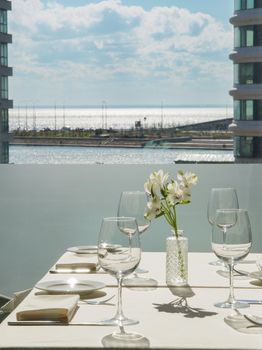 A beautifully set table on a balcony overlooking the serene ocean, ideal for elegant al fresco dining.