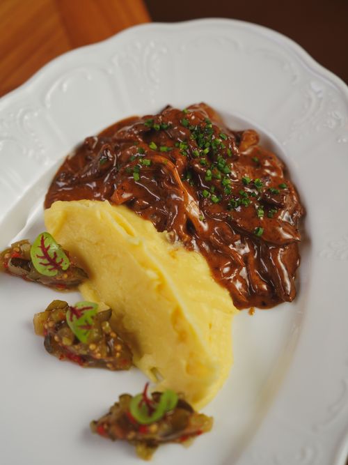 Free Appetizing gourmet dish featuring mashed potatoes and savory meat sauce, garnished with chives for a perfect meal. Stock Photo