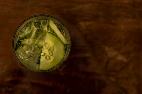 Free Top view of a cucumber cocktail with ice cubes on a wooden table. Stock Photo