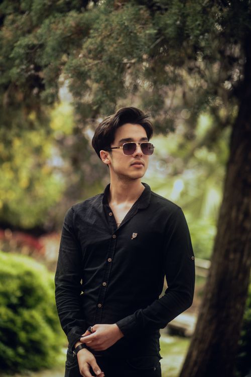 Free A fashionable young man in sunglasses poses outdoors with a confident look. Stock Photo