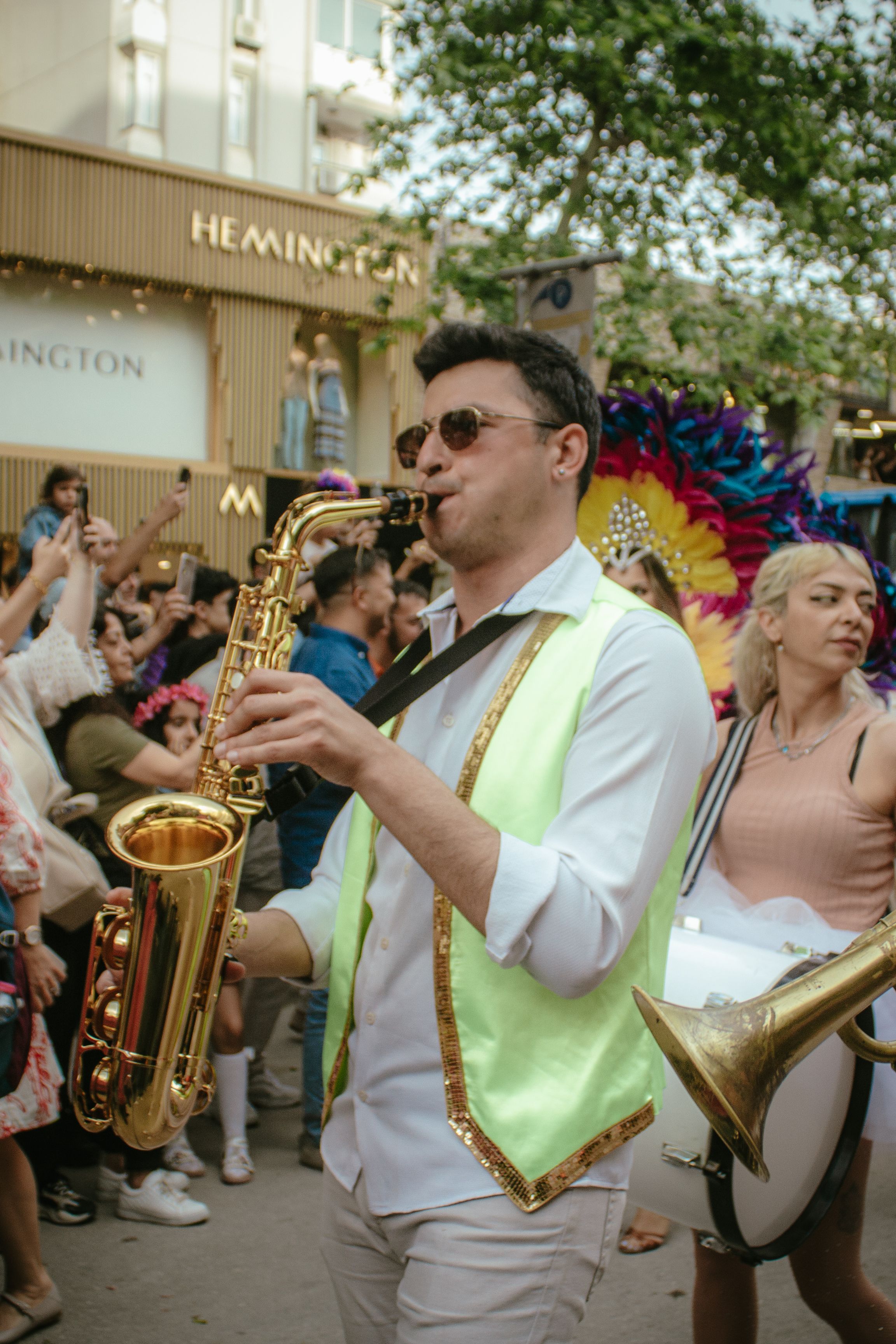 Musician playing saxophone at vibrant parade in Adana, Türkiye.