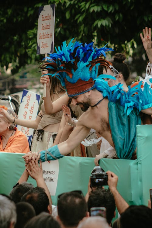 A man in a blue feather costume is holding a sign