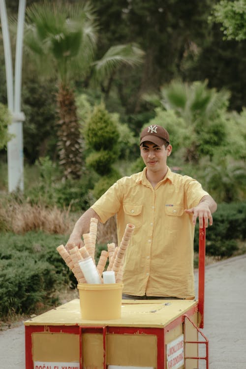 A man in a yellow shirt is standing next to a cart