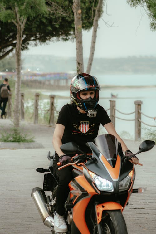 A man on a motorcycle rides by a lake