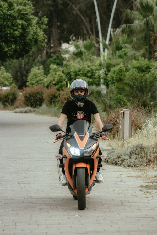 A man riding an orange motorcycle down a path