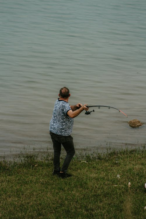 A man fishing in the water near a lake