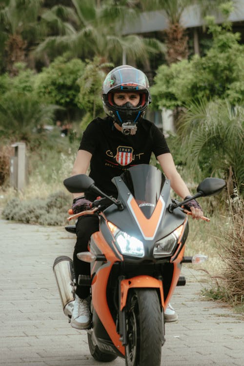 A person in a helmet riding an orange motorcycle