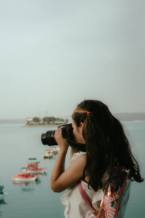 A girl taking a photo of boats in the water