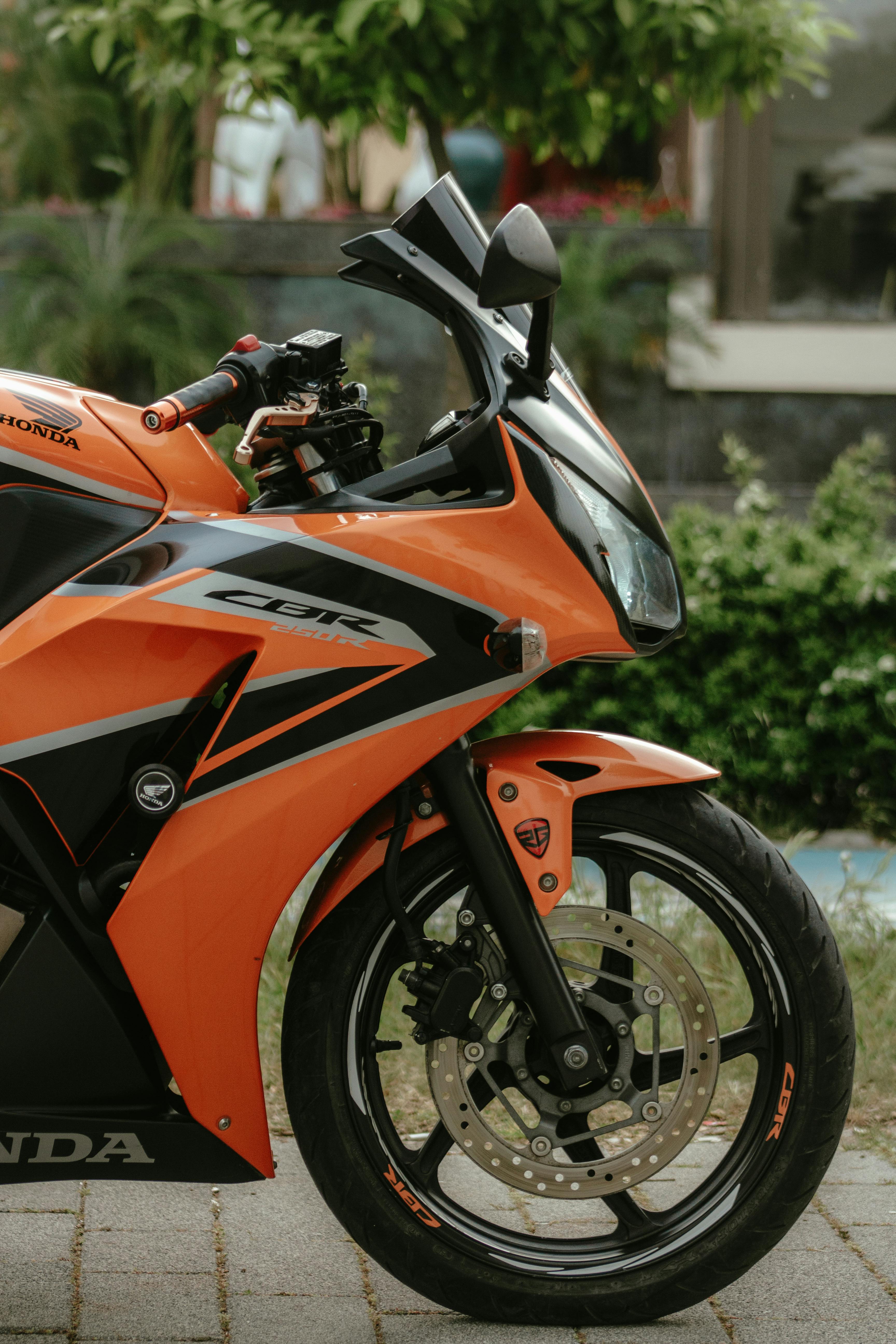 Vibrant orange Honda CBR 250R motorcycle parked outdoors, showcasing sleek design.
