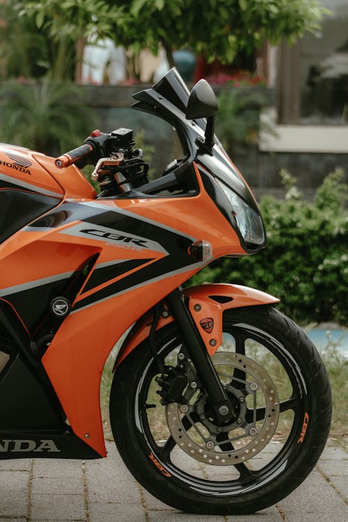 An orange and black motorcycle parked on the side of the road