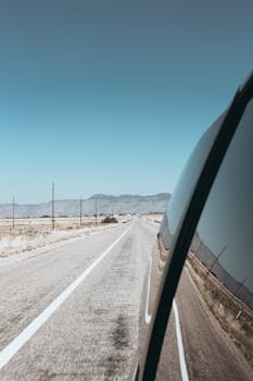 从汽车侧面的镜子中，拍到了亚利桑那州沙漠高速公路上优美的驾驶风景