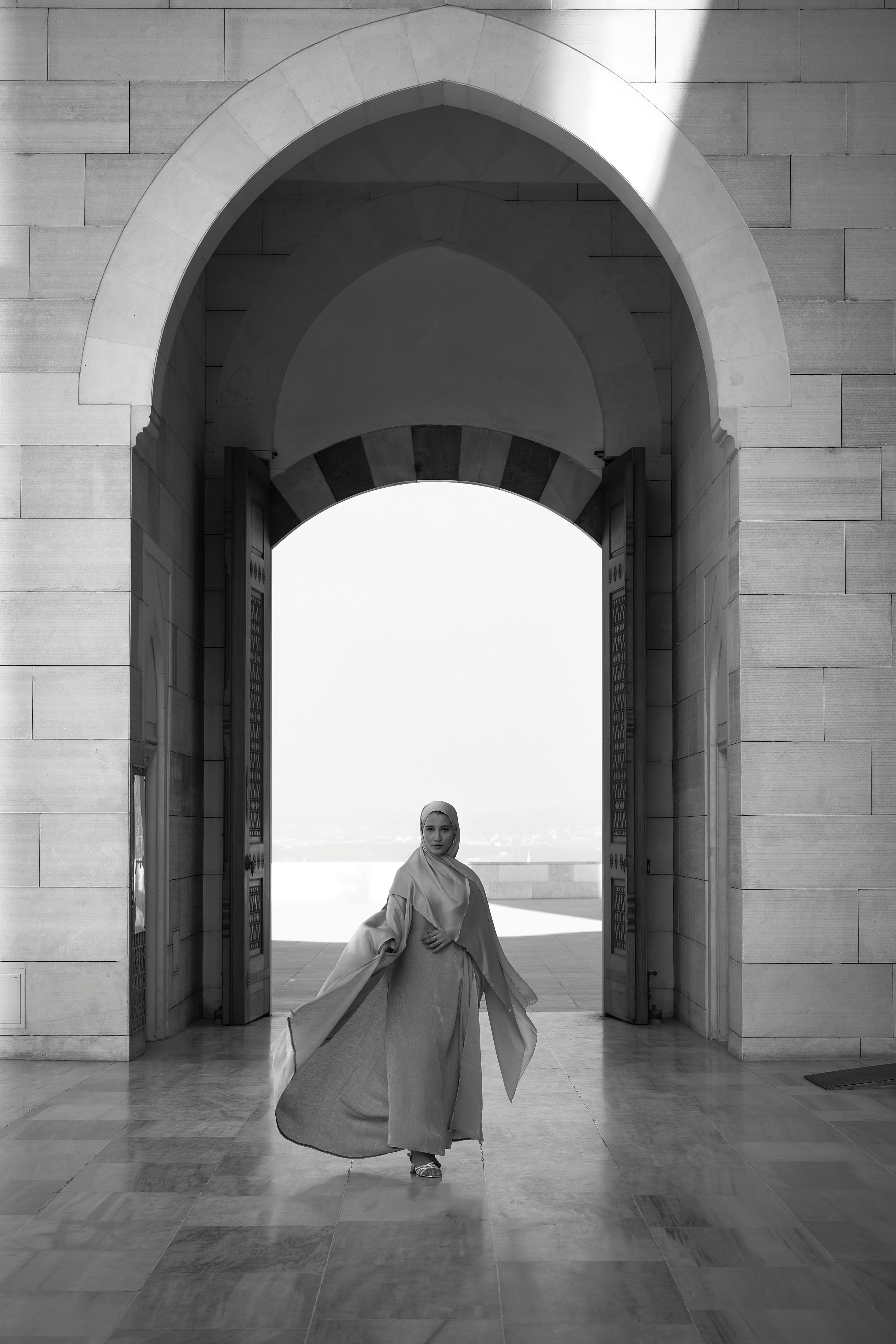 A woman in a hijab poses gracefully in a grand palace setting, capturing elegance and Muslim fashion.