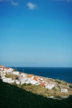 Aerial view of a charming town on Tenerife's coast with clear skies and sea in the background.