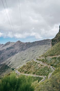 Explore the scenic winding road through Tenerife's mountainous landscape under a cloudy sky.