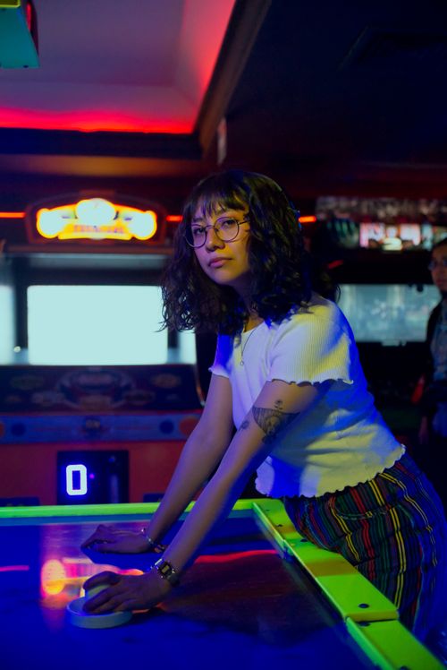Free Young woman in an arcade playing air hockey in vibrant lighting, Ciudad de México. Stock Photo