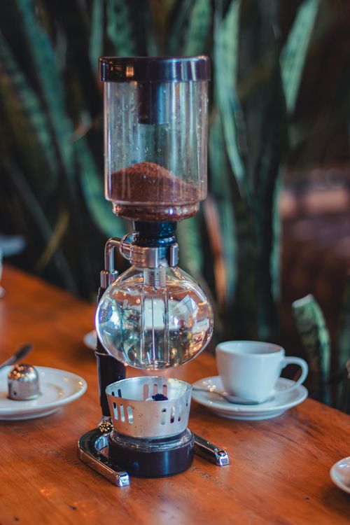 Free Stylish syphon coffee maker setup on a wooden table with cups, enhancing a classic and vintage vibe. Stock Photo