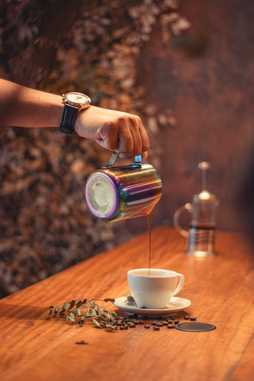 A Person Pouring Coffee from a Pot into a Cup