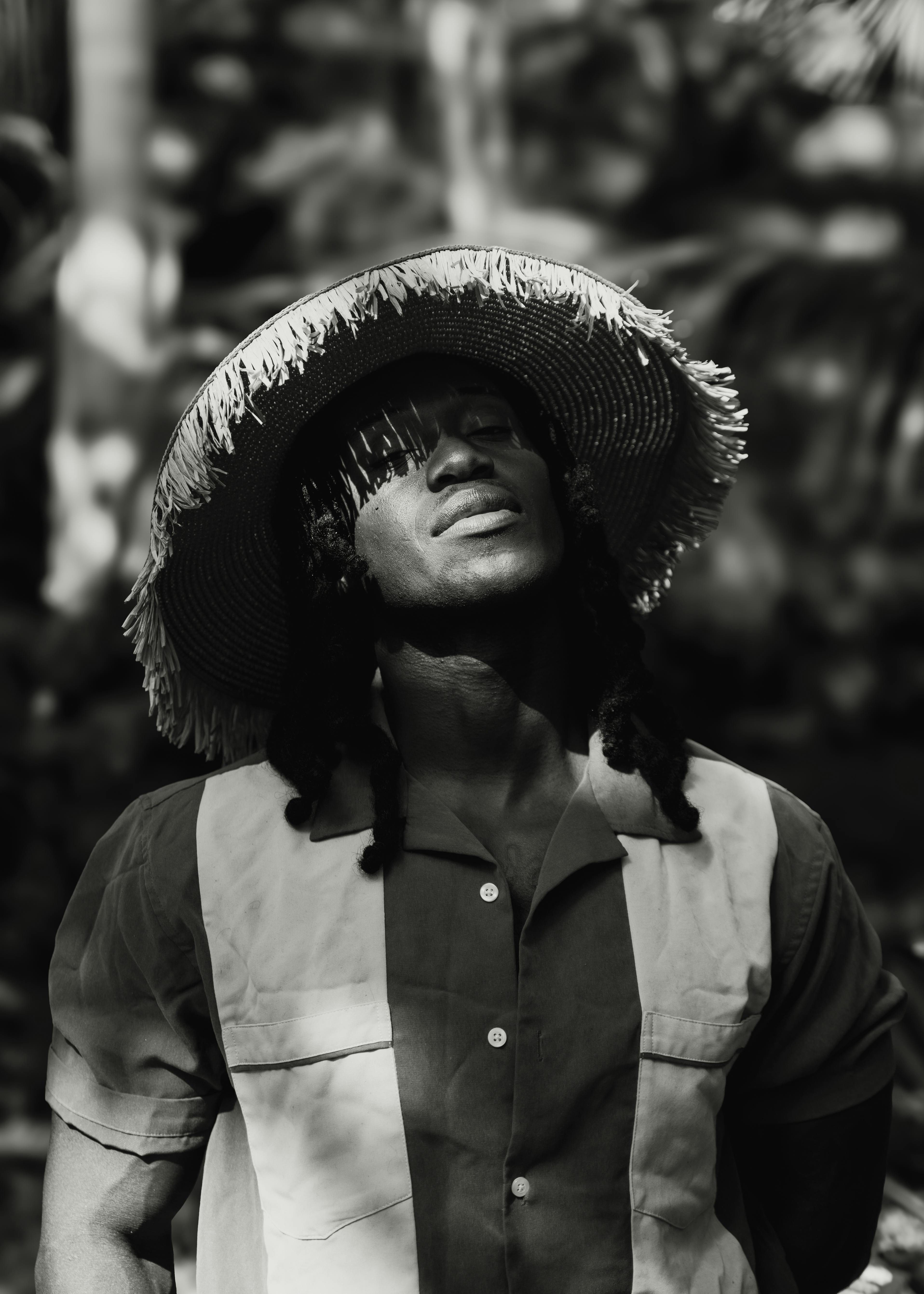 Striking monochrome portrait of a man wearing a straw hat and casual shirt.