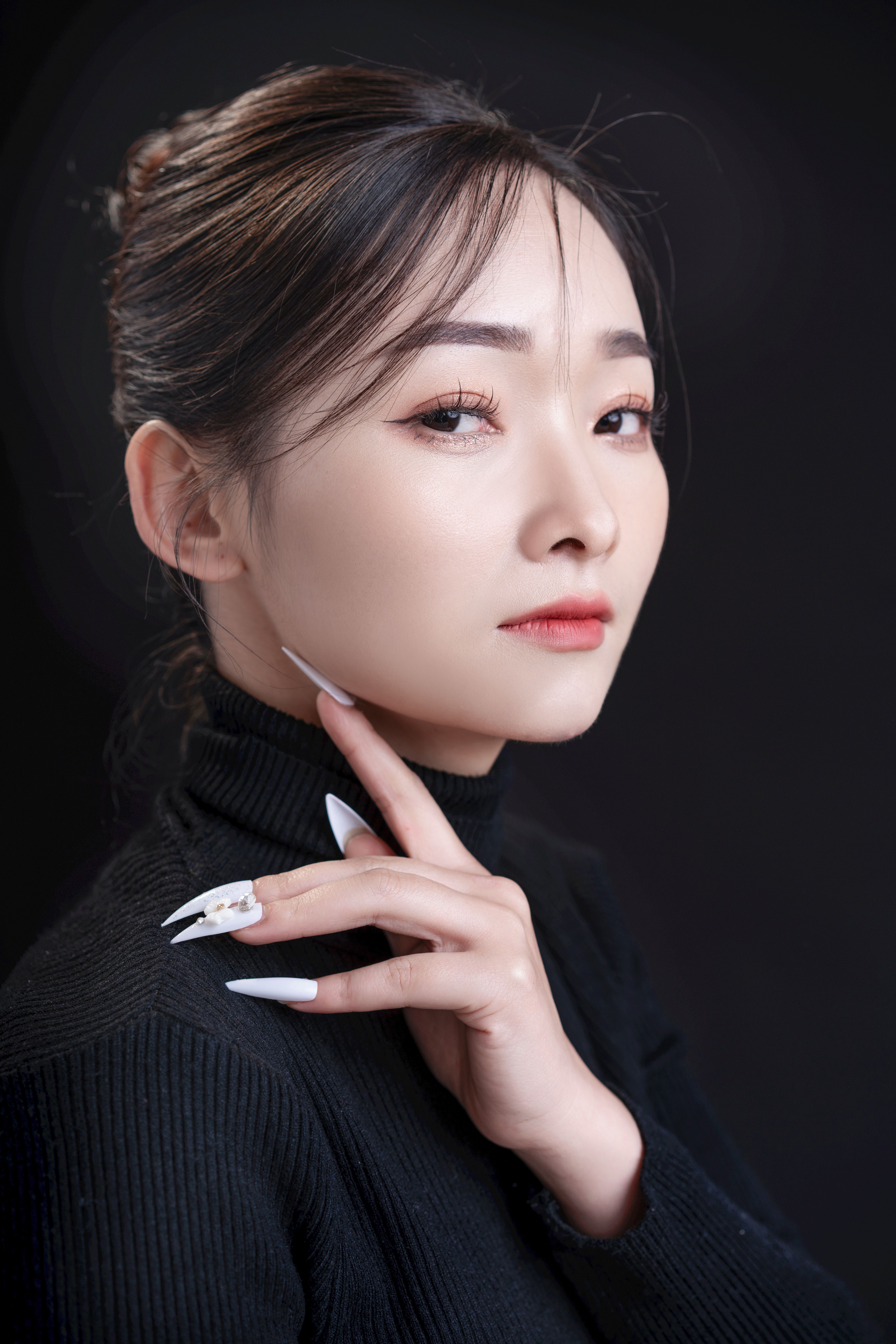 Stylish portrait of an Asian woman in a black turtleneck against a dark background, exuding elegance and poise.