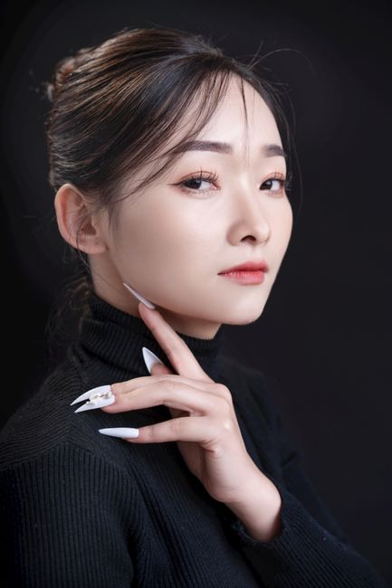Stylish portrait of an Asian woman in a black turtleneck against a dark background, exuding elegance