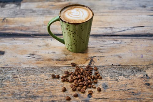 コーヒー豆とテーブルの上のカプチーノのマグカップ