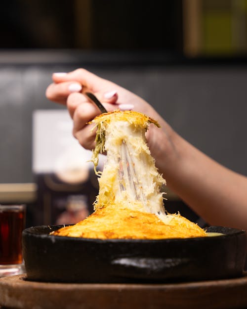 A person is holding a fork over a piece of cheese