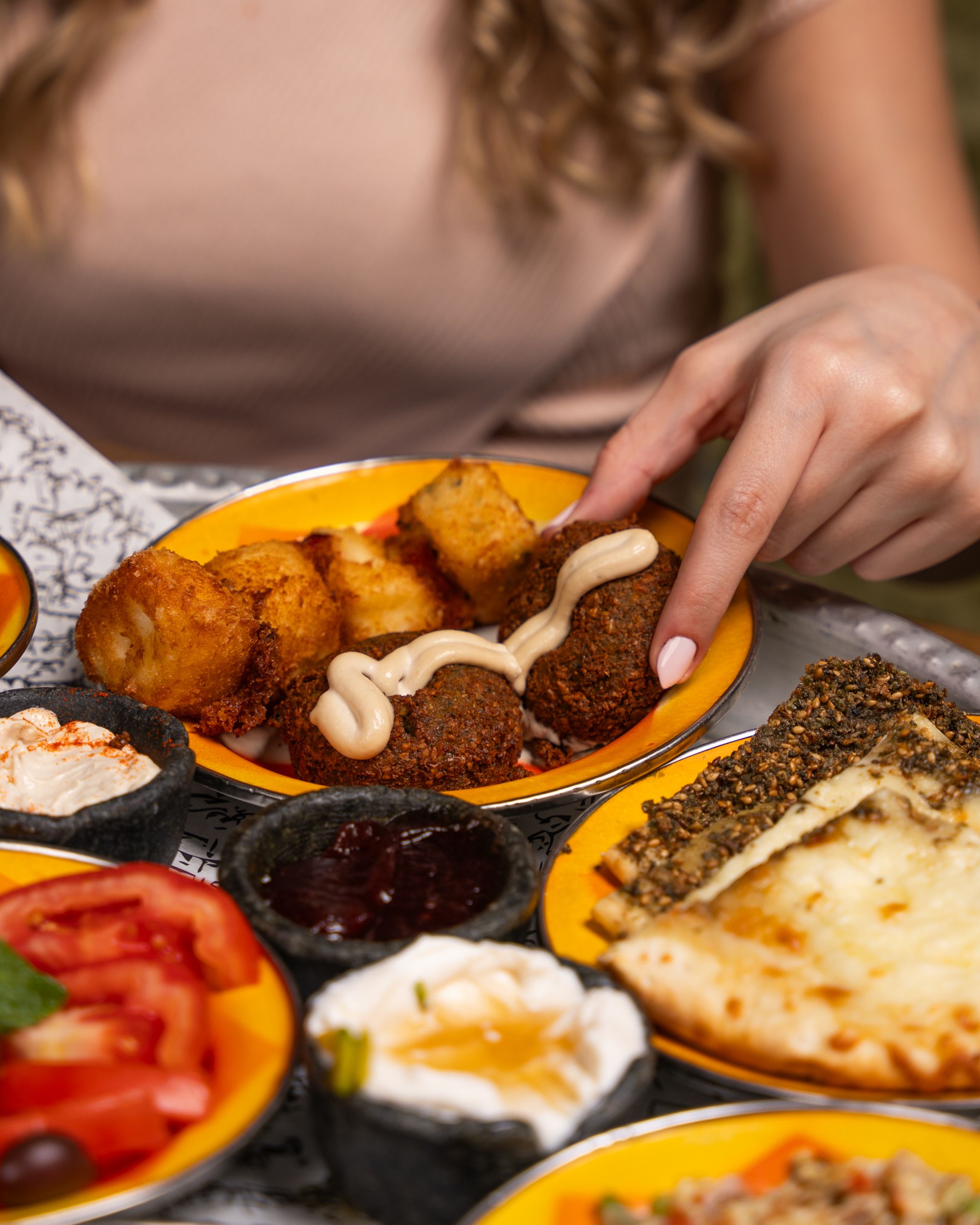 Colorful Middle Eastern mezze platter featuring falafel, dips, and bread on vibrant plates.