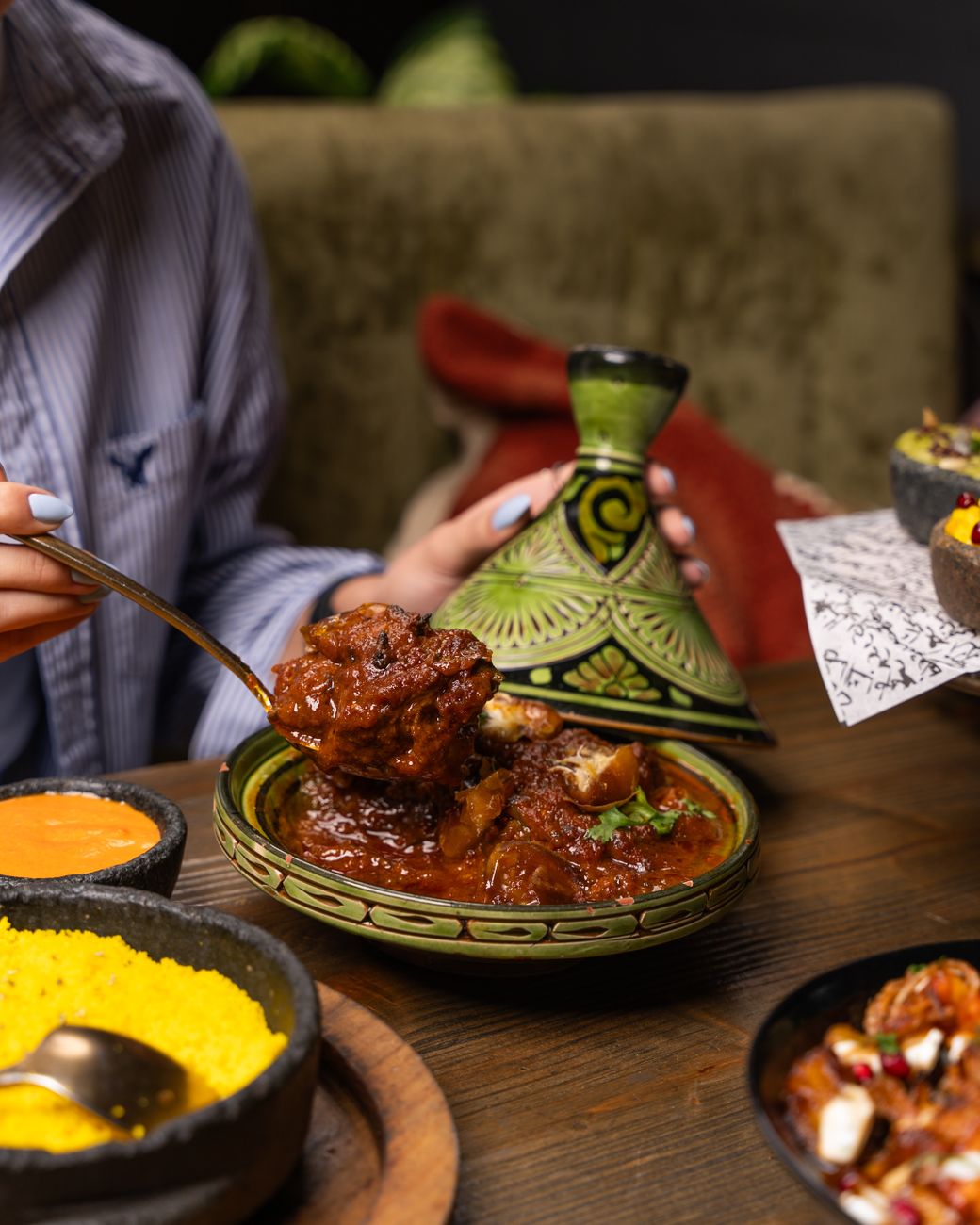 Rich, dark red lamb tagine with tender meat, dried apricots, and fresh cilantro in a traditional ceramic serving bowl