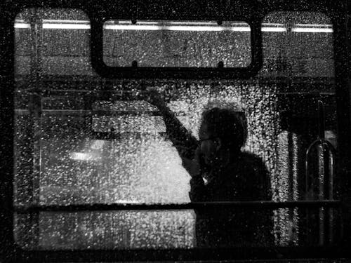 A man is standing in the rain on a train