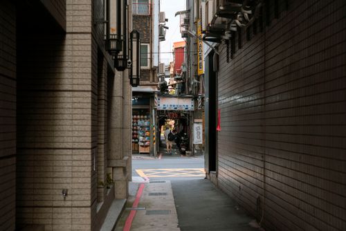 Free A narrow alleyway in an urban setting with brick walls and shadowed pavement. Stock Photo
