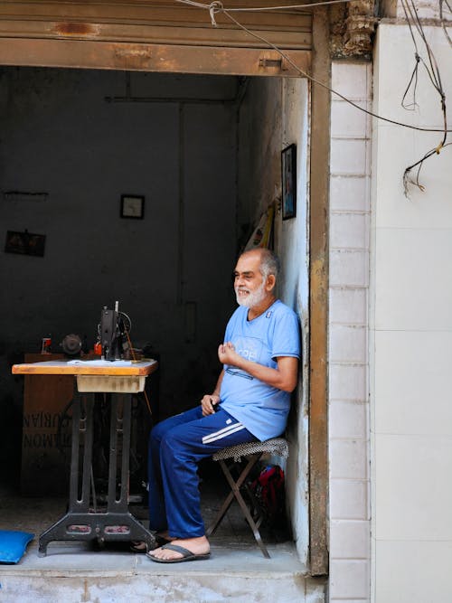 A man sitting in a doorway with a sewing machine