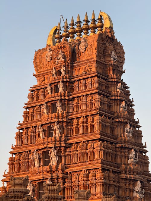 The hindu temple is made of stone and has many statues