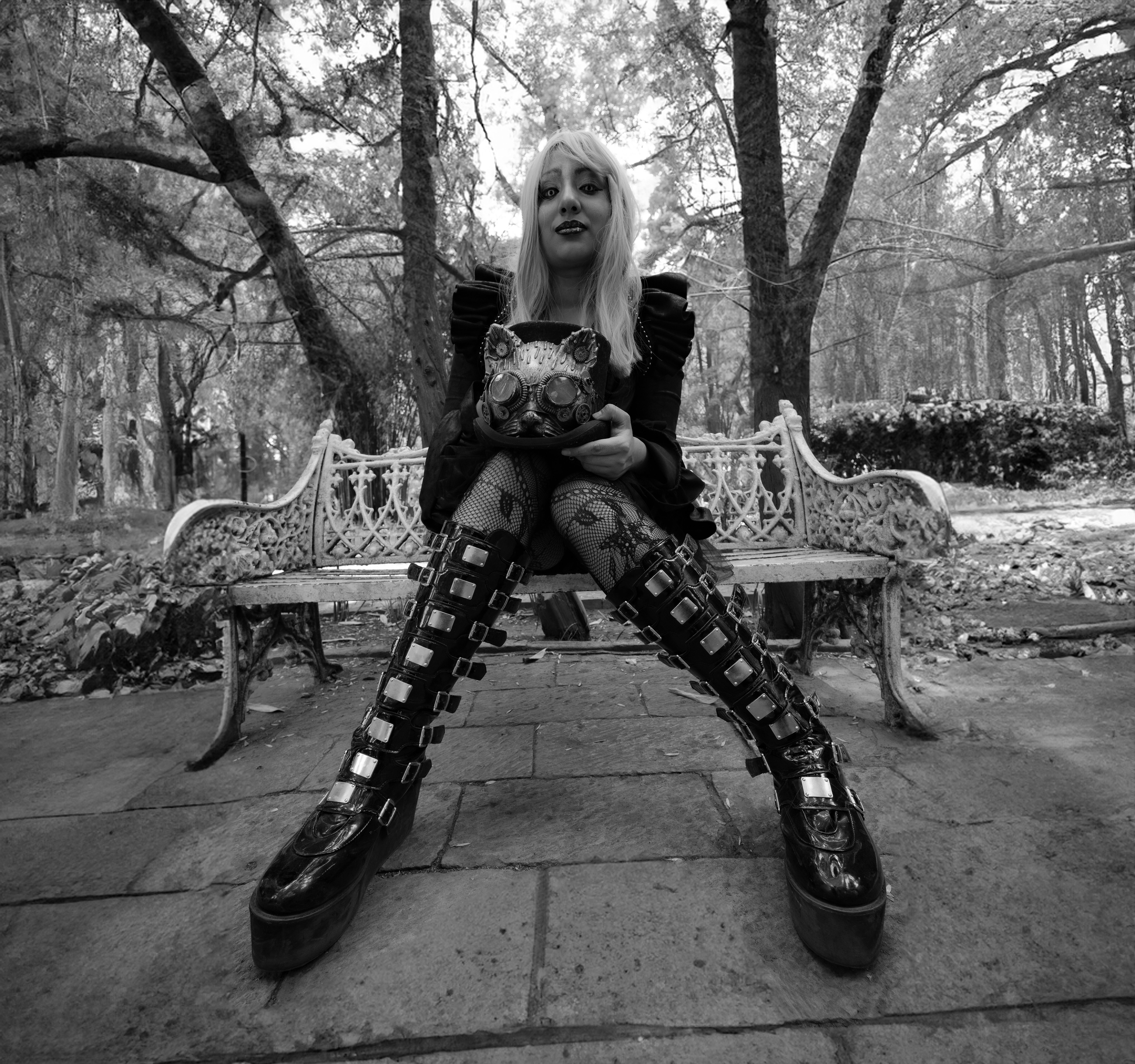 Black and white photo of a woman in gothic attire on a park bench in Mexico City.