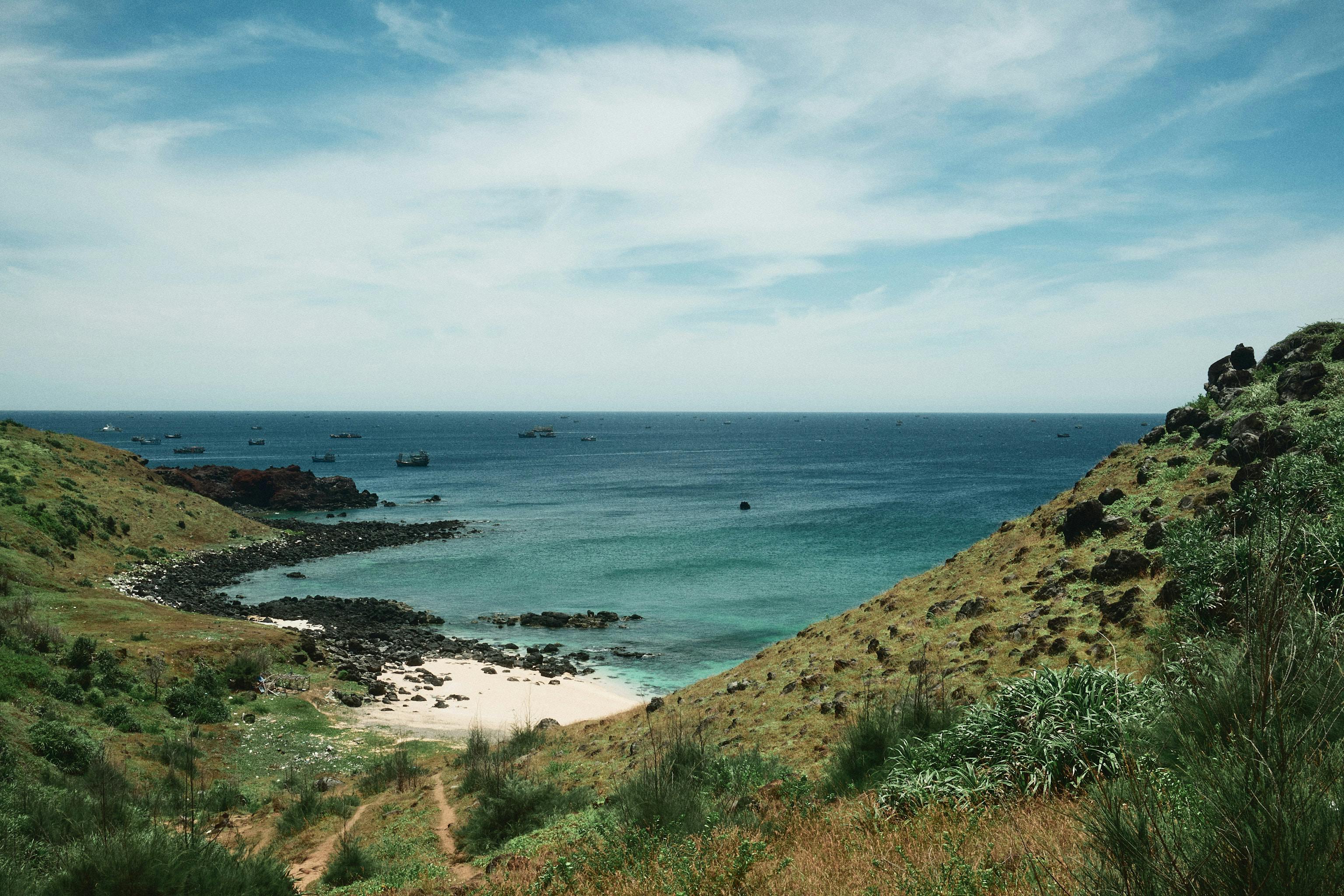 Beautiful coastal landscape of Phú Quý Island with clear blue waters and lush green hills.