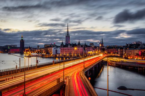 Free Stunning long exposure shot of Stockholm's illuminated cityscape and Centralbron Bridge at dusk. Stock Photo