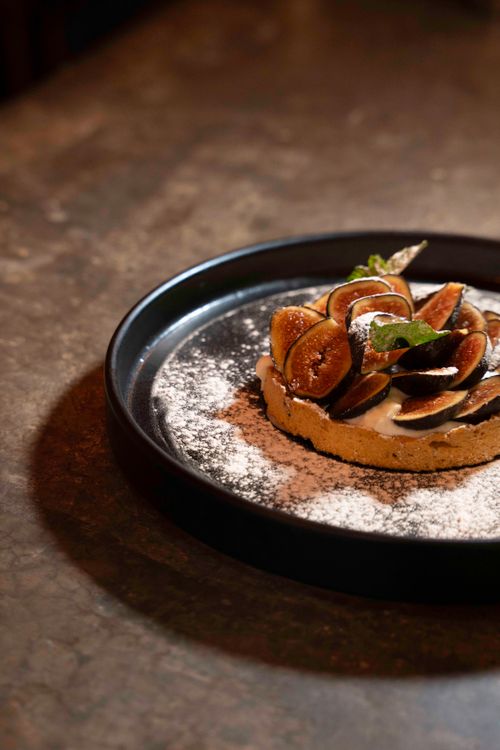 Free Gourmet fig tart on a black plate, dusted with powdered sugar, perfect for dessert inspiration. Stock Photo
